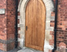 Bespoke arched Douglas Fir timber door installed within stone Gothic arch in West Stockwith conservation area