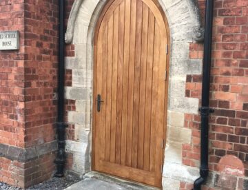 Bespoke arched Douglas Fir timber door installed within stone Gothic arch in West Stockwith conservation area