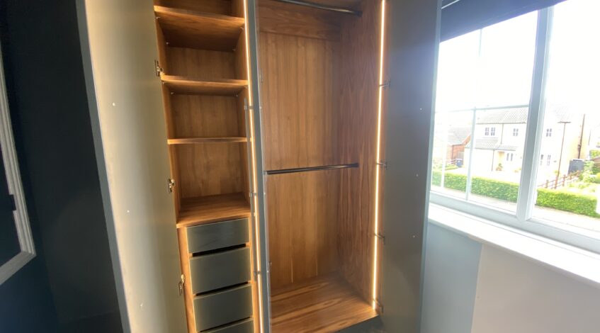 Walnut veneered interior with integrated LED lighting in fitted wardrobe Navenby