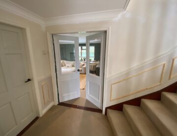 Painted bespoke internal double doors with glazed upper panels installed beside staircase in Lincoln home.