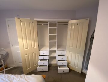 Bespoke wardrobe storage in Lincoln with multiple fitted drawers and central shelving unit.